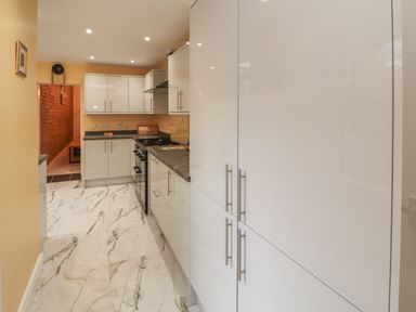 A kitchen with white cabinets gray countertops and marble floor at The Furness Haven in Barrow-In-Furness