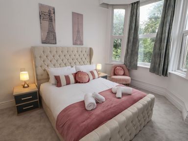 A bedroom with a bed and side tables with lamps and a chair near windows with curtains at The Furness Haven in Barrow-In-Furness