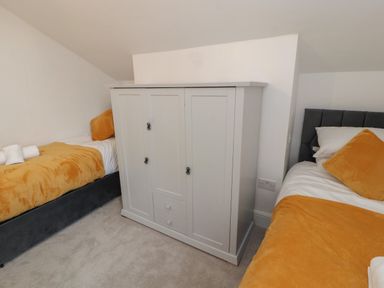 A bedroom with two single beds and a white wardrobe in the middle at The Furness Haven in Barrow-In-Furness