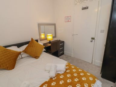 A bedroom with a bed with two pillows a desk with a lamp a mirror a door and a wardrobe at The Furness Haven in Barrow-In-Furness