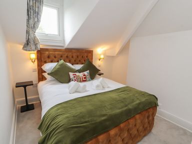 A bedroom with a bed green pillows green blanket and two bedside tables at The Furness Haven in Barrow-In-Furness