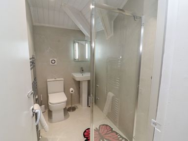 A bathroom with a toilet sink mirror glass shower and towel rack at The Furness Haven in Barrow-In-Furness
