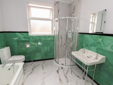 A bathroom with a toilet bathtub sink shower and green tiles at The Furness Haven in Barrow-In-Furness