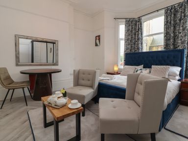 A bedroom with a bed a small wooden table and a round table with chairs at The Furness Haven in Barrow-In-Furness