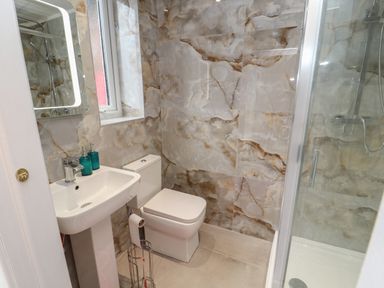 A bathroom with a sink a toilet a shower and a window at The Furness Haven in Barrow-In-Furness