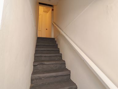 A stairway with black steps and white handrail leading to an open door at The Furness Haven in Barrow-In-Furness