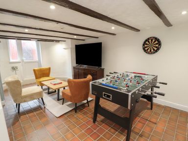 A game room with a foosball table a dartboard a television and four chairs around a coffee table at The Furness Haven in Barrow-In-Furness