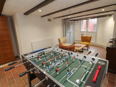 A room with a foosball table a small seating area with three chairs and a table at The Furness Haven in Barrow-In-Furness