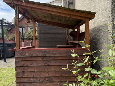 A wooden structure with a roof and counter in a garden at The Furness Haven in Barrow-In-Furness