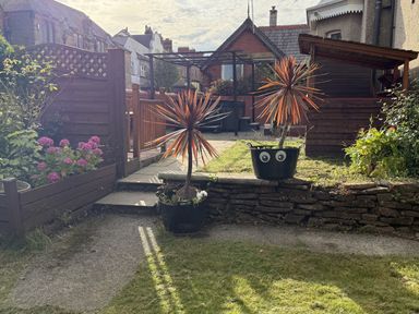A garden with flower bed, paving stones, and plants at The Furness Haven in Barrow-In-Furness