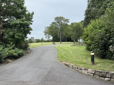 A pathway leading to a bench surrounded by trees and grass at The Furness Haven in Barrow-In-Furness