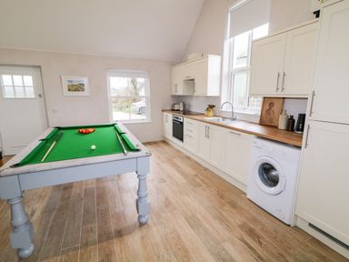 A kitchen with a pool table dishwasher washing machine and cabinets at The Poets Cottage in Portglenone