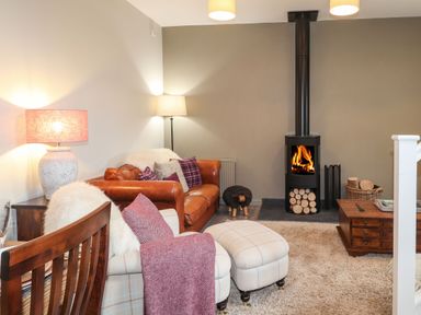 A living room with a leather sofa a fireplace and wooden furniture at The Pottery in Newport Pembrokeshire