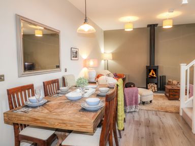 A dining area with a wooden table set for four and a living room with a wood stove and seating at The Pottery in Newport Pembrokeshire