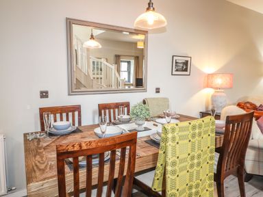 A dining table set with dishes and glasses with wooden chairs and a large mirror on the wall at The Pottery in Newport Pembrokeshire