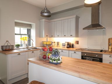 A kitchen with wooden countertops white cabinets a stainless steel oven and a fruit basket at The Pottery in Newport Pembrokeshire