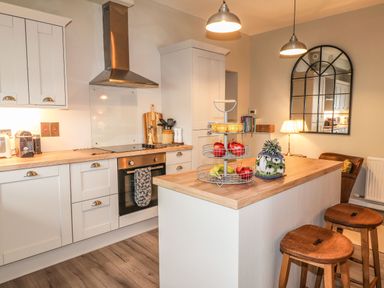 A kitchen with wooden countertops a stove and oven fruit basket stools and a wall mirror at The Pottery in Newport Pembrokeshire