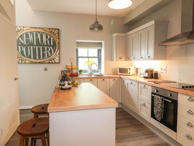 A kitchen with wooden countertops stools and appliances with Newport Pottery sign on the wall at The Pottery in Newport Pembrokeshire