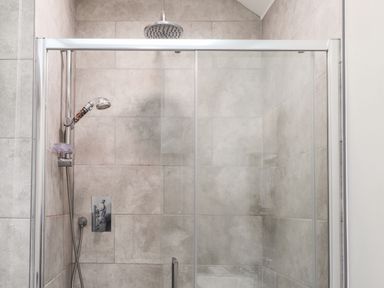 A shower area with tiled walls and a glass door at The Pottery in Newport Pembrokeshire