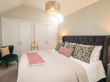 A bedroom with a large bed green chair and two closets at The Pottery in Newport Pembrokeshire