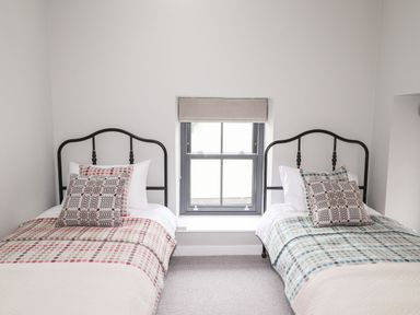 A bedroom with two single beds and a window with a blind between them at The Pottery in Newport Pembrokeshire