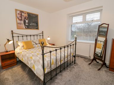 A bedroom with a double bed two bedside tables with lamps a standing mirror and a window at Bronwen House in Llanbedr