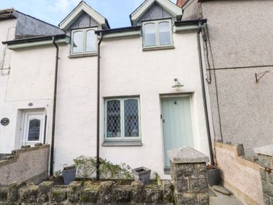 A white house with two dormer windows a green door numbered 4 and a small garden in front at Ty Crydd in Llansaint near Kidwelly