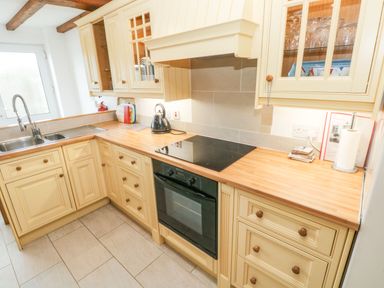 A kitchen with a sink a kettle an oven and wooden cabinets at Ty Crydd in Llansaint near Kidwelly