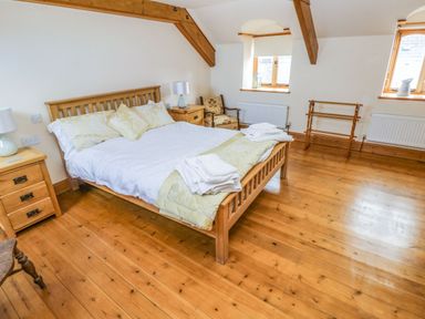 A bedroom with a wooden bed bedside tables and wooden floors at Ty Crydd in Llansaint near Kidwelly