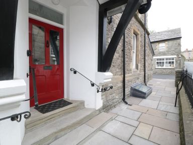 An entrance with a red door and steps leading to a stone-paved walkway beside a stone building at Belle Vue in Hay on Wye Herefordshire