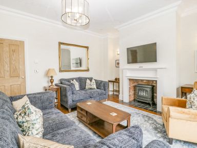A living room with gray sofas a wooden coffee table a fireplace with a mounted TV and an armchair at Belle Vue in Hay on Wye Herefordshire