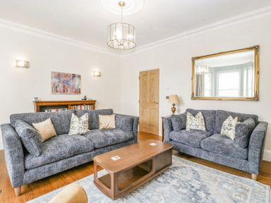 A living room with two grey sofas a wooden coffee table a large wall mirror and a bookshelf at Belle Vue in Hay on Wye Herefordshire