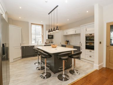 A kitchen with an island and five black bar stools pendant lights window and built in appliances at Belle Vue in Hay on Wye Herefordshire