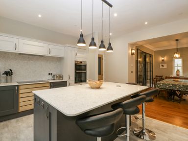 A kitchen with a large island and black bar stools next to a dining area at Belle Vue in Hay on Wye Herefordshire