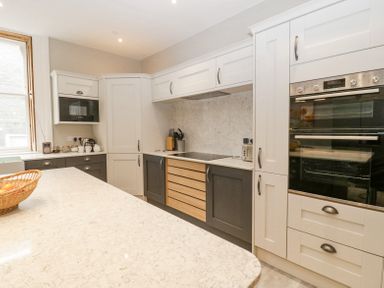 A kitchen with white and dark gray cabinets a built in oven a microwave and a countertop with a basket of fruit at Belle Vue in Hay on Wye Herefordshire