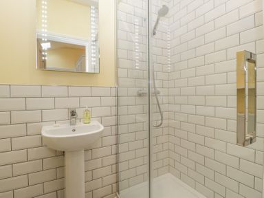 A bathroom with a pedestal sink and a glass-enclosed shower with tiled walls at Belle Vue in Hay on Wye Herefordshire