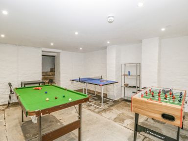A games room with a pool table, table tennis table, foosball table, metal shelving unit and two chairs at Belle Vue in Hay on Wye Herefordshire