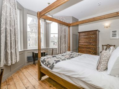 A bedroom with a wooden four-poster bed and chest of drawers by the window at Belle Vue in Hay on Wye Herefordshire