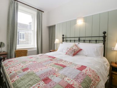 A bedroom with a metal bed frame patchwork quilt bedside tables and a window at Belle Vue in Hay on Wye Herefordshire
