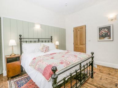 A bedroom with a metal bed frame wooden floor and lamps on side tables at Belle Vue in Hay on Wye Herefordshire