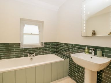 A bathroom with a bathtub sink and green tiled walls at Belle Vue in Hay on Wye Herefordshire