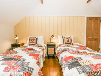 A bedroom with two single beds with colorful patchwork quilts and bedside tables with lamps at Belle Vue in Hay on Wye Herefordshire