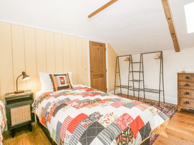 A bedroom with a single bed a bedside table with lamp a wooden dresser and clothing racks at Belle Vue in Hay on Wye Herefordshire