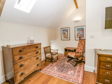 A room with wooden dressers a patterned rug vintage chairs and framed artwork on the wall at Belle Vue in Hay on Wye Herefordshire
