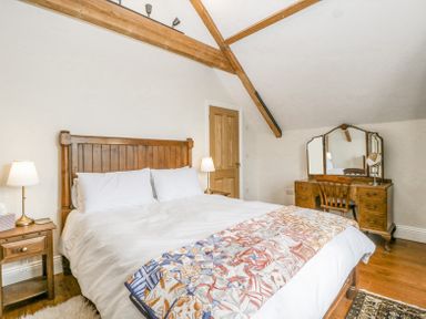 A bedroom with a wooden bed white bedding bedside tables lamps and a wooden dressing table with a chair at Belle Vue in Hay on Wye Herefordshire