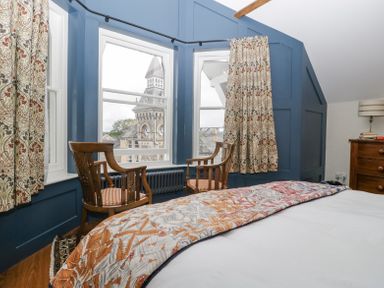A bedroom with two wooden chairs by windows showing a clock tower outside at Belle Vue in Hay on Wye Herefordshire