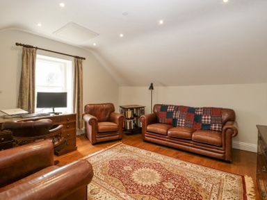 A room with leather armchairs and sofa a desk with computer and a patterned rug at Belle Vue in Hay on Wye Herefordshire
