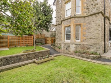A garden with green grass trees wooden planters and a stone building at Belle Vue in Hay on Wye Herefordshire
