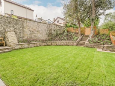 A garden with a lawn facing stone walls steps and trees at Belle Vue in Hay on Wye Herefordshire