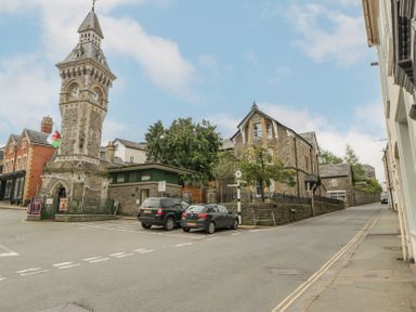 A street view with a stone clock tower two parked cars and stone buildings at Belle Vue in Hay on Wye Herefordshire
